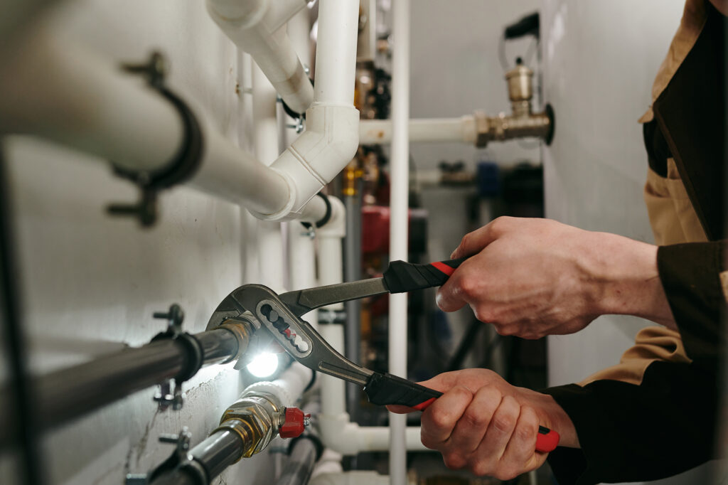 Repairman using a tool to fix parts of pipes during work